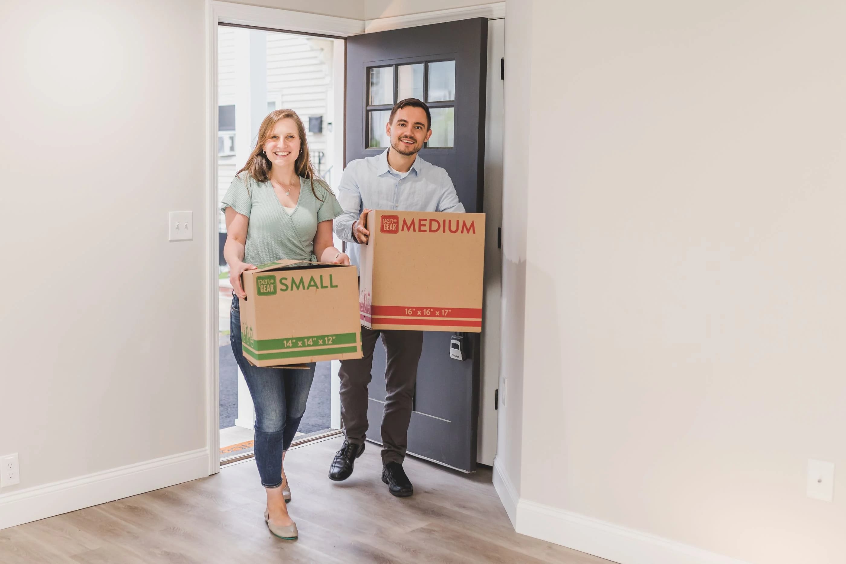 A couple carrying moving boxes into their new home