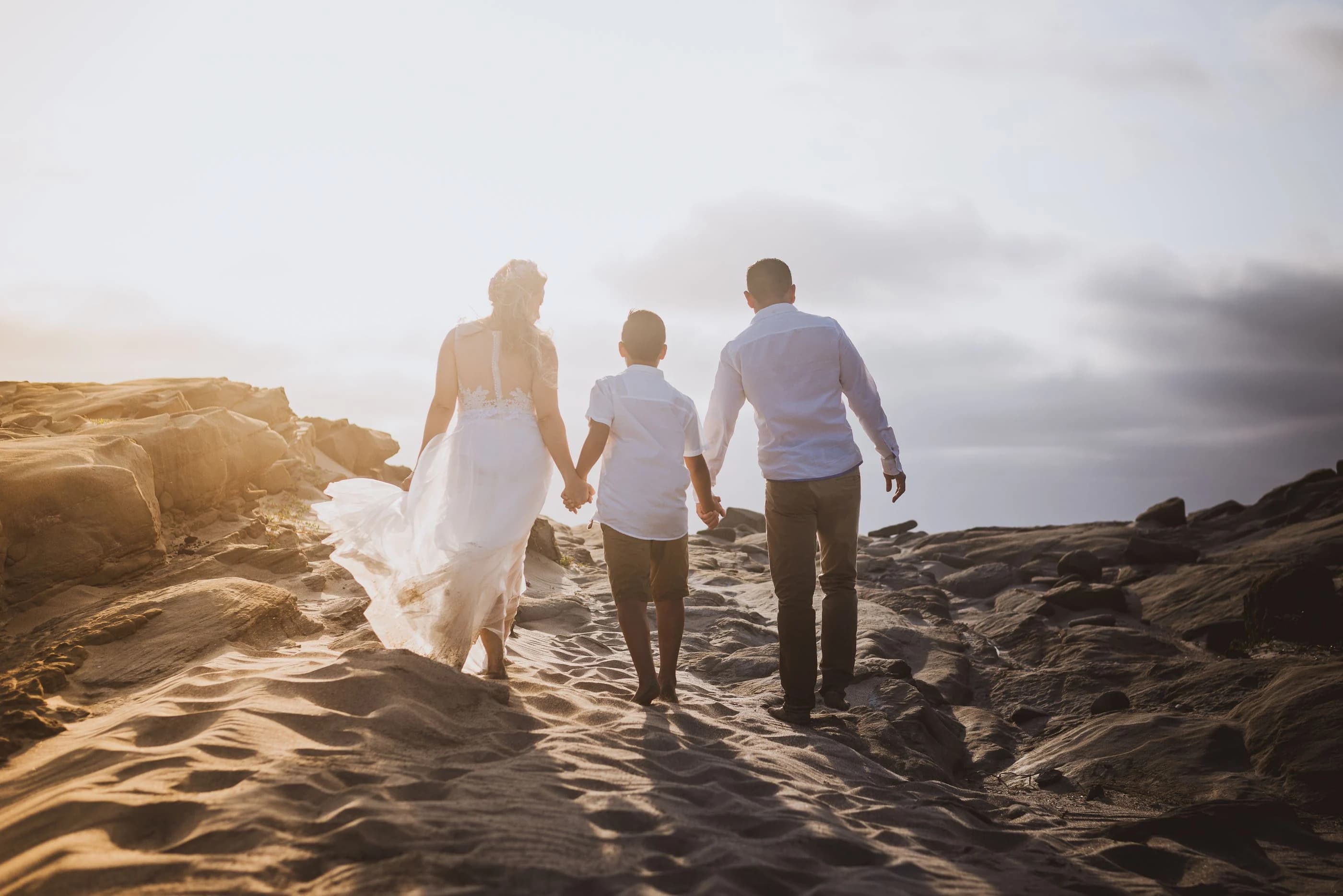 A family holding hands while walking on a sandy beach