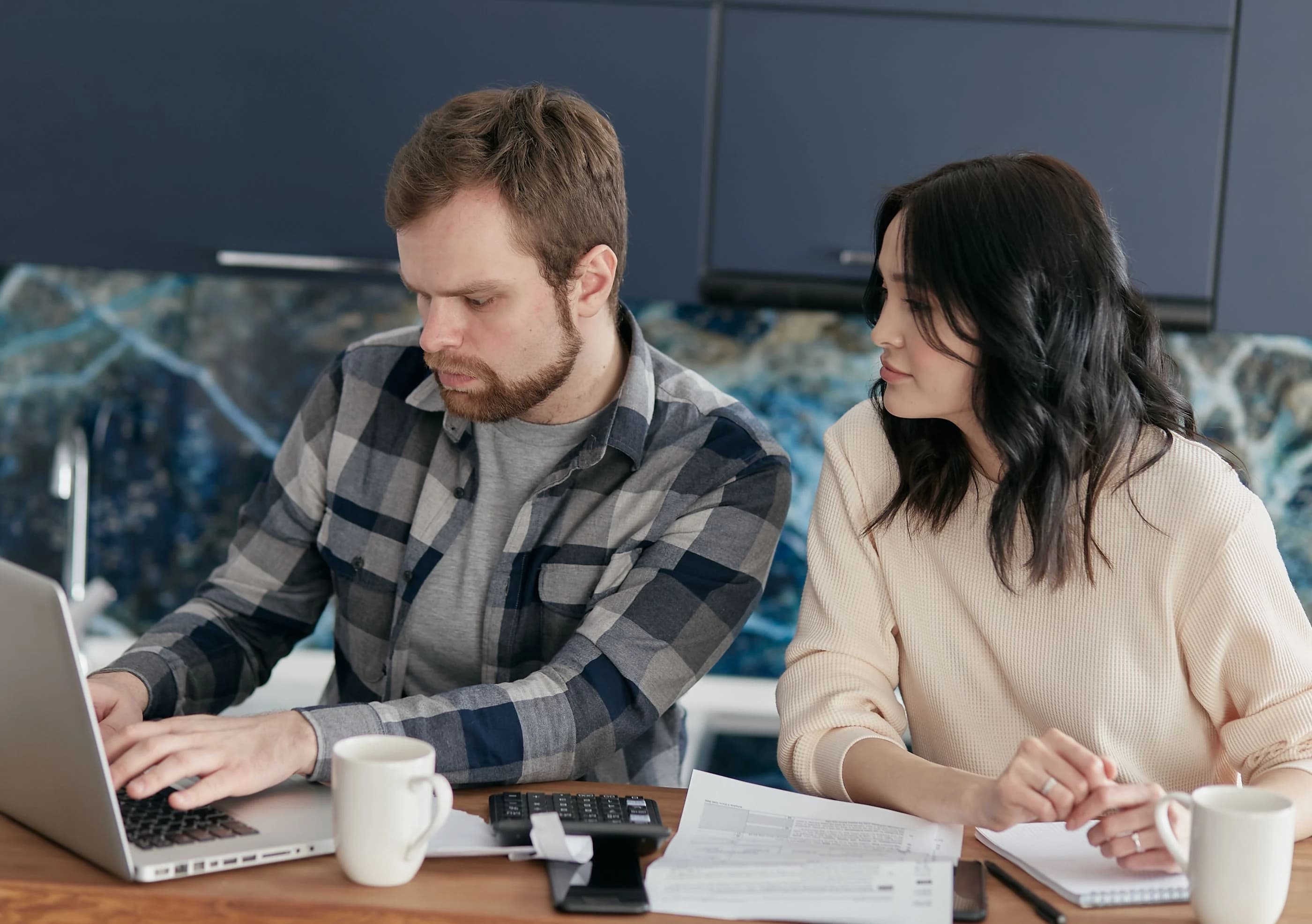 A couple reviewing paperwork and a laptop together at home